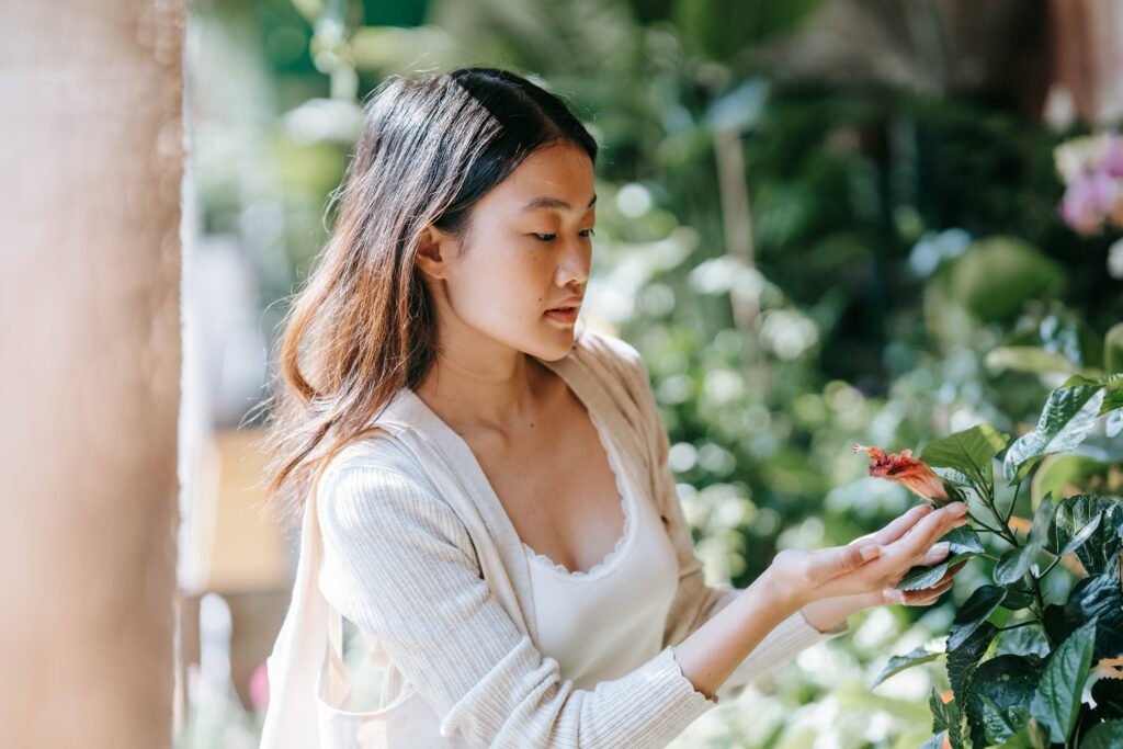 Une femme observant une fleur, en connexion à son environnement pour revenir au sens de la vie